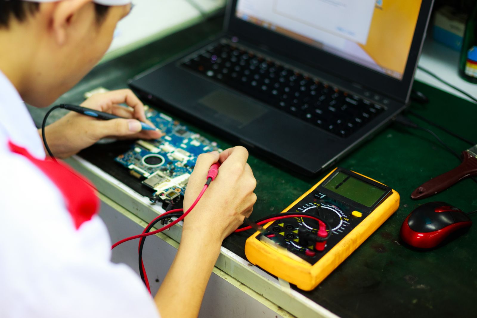 Technicien testant un ordinateur portable avec un multimetre