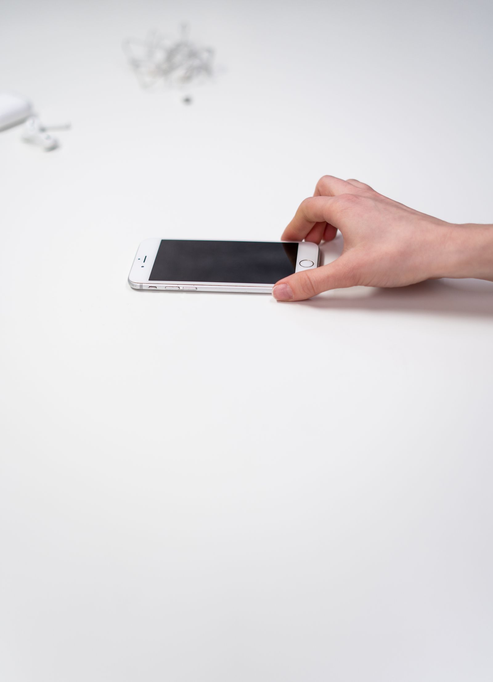 Main tenant un smartphone sur une surface claire