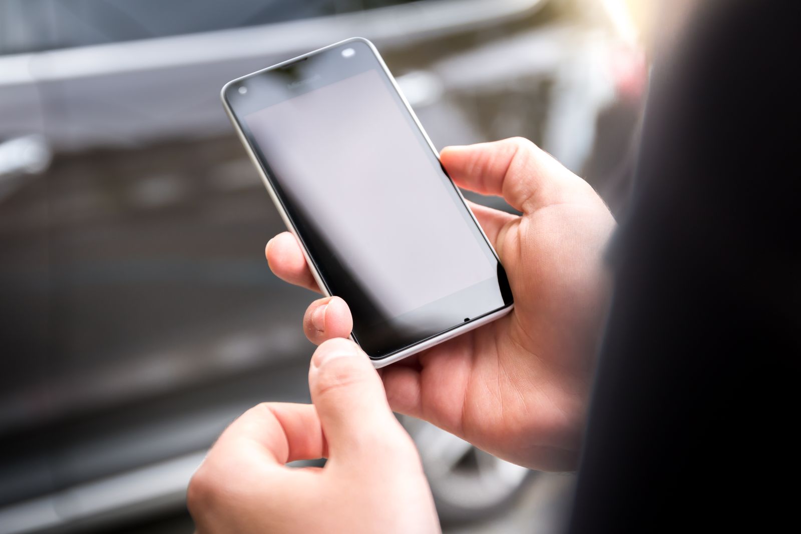 Mains tenant un smartphone en exterieur