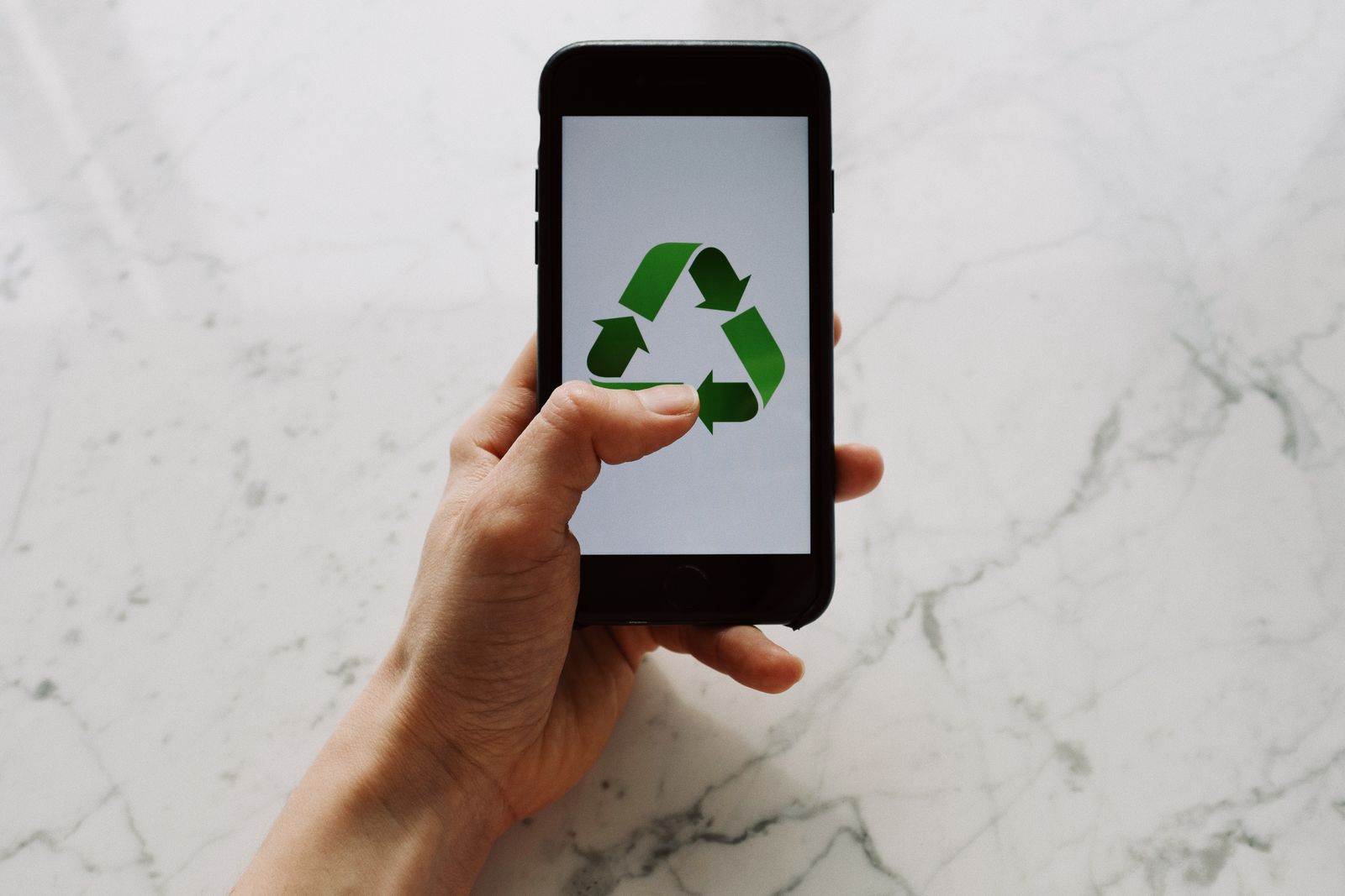 Main tenant un smartphone avec symbole de recyclage